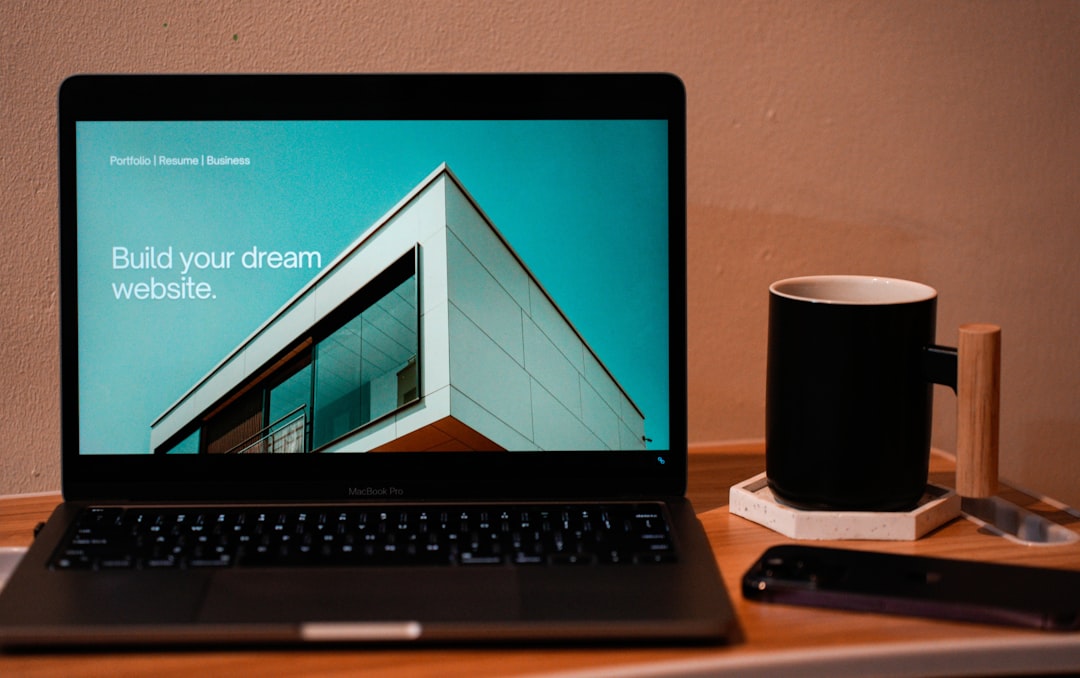 services-02 Build your dream website for your future. A laptop, MacBook, on top of a portable table with coffee tea mug on the side.